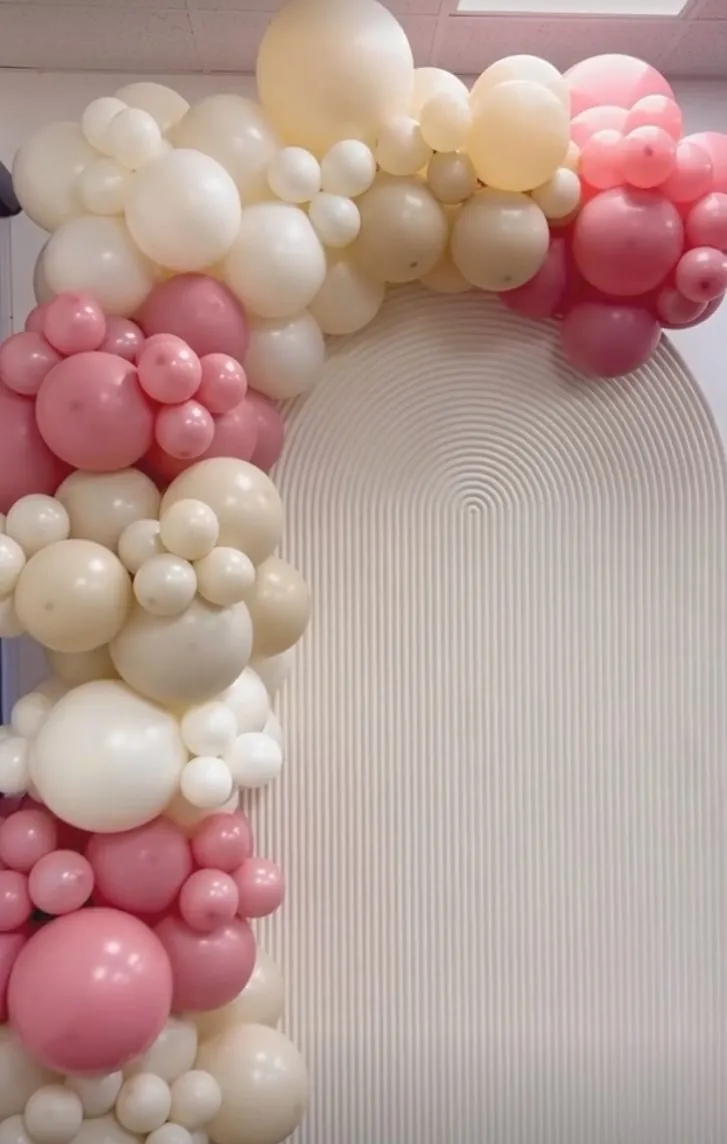 Blush and cream balloon garland on a white arch